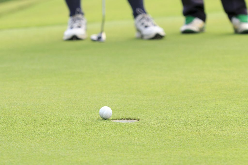 En boll rullar in i ett golfhål.