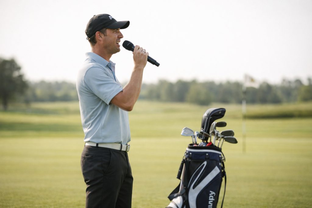 En eventledare pratar på en golfklubb i en mikrofon.